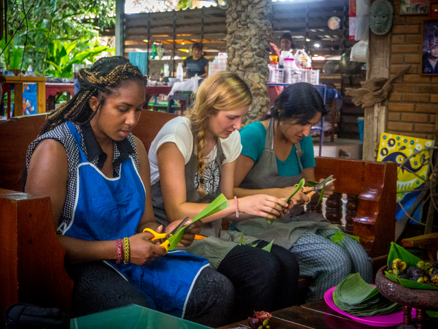 Guests Liz, from London, Jasmine from Switzerland and Jeevan from Canada cut banana leaf ready for wrapping sweet sticky rice desserts