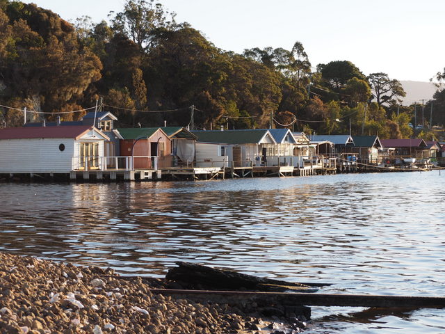 The Cornelian Bay Boatsheds sit over water at the edge of a cove near Hobart